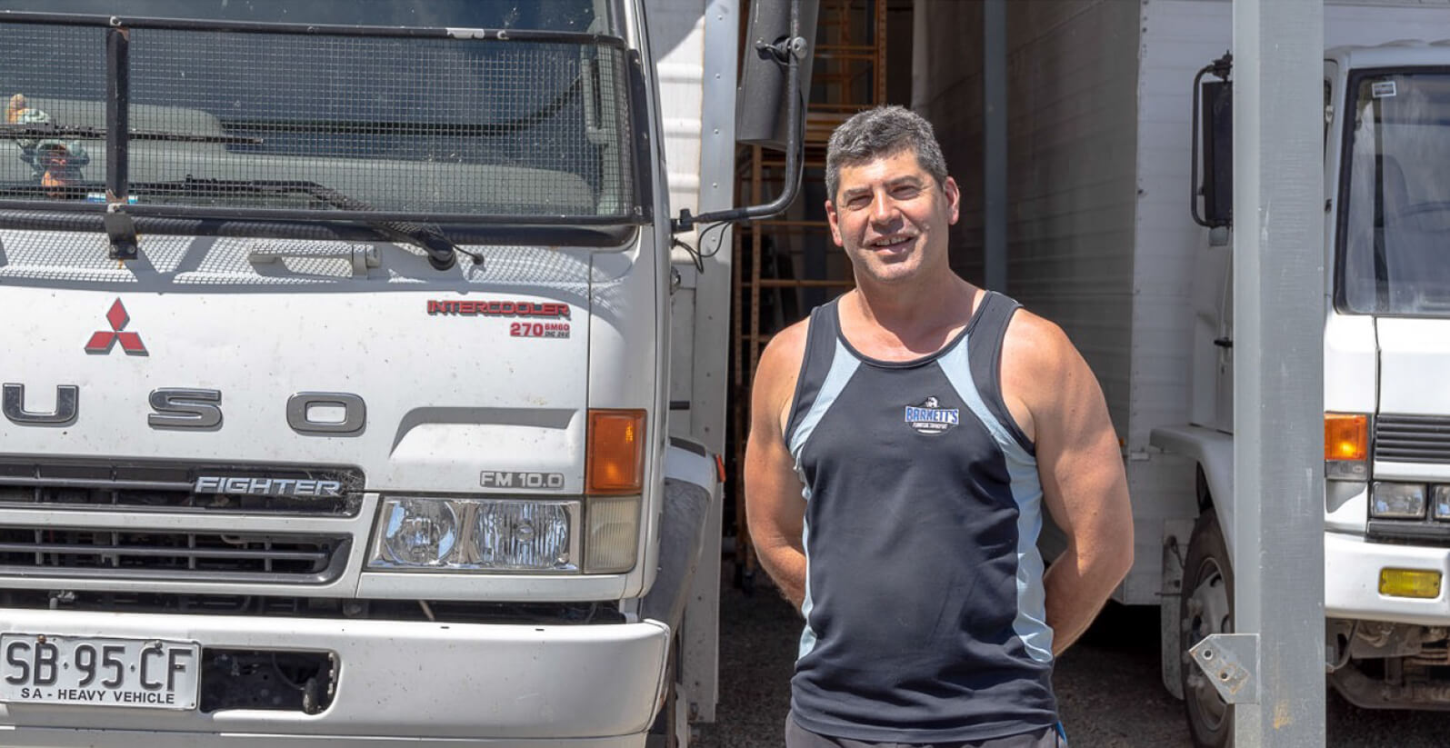 Closeup of male outside standing in front of two removal trucks