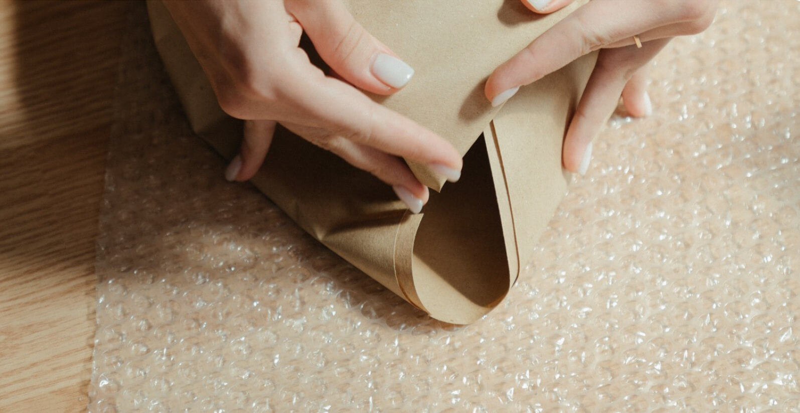 Woman folding packing paper on top of bubble wrap