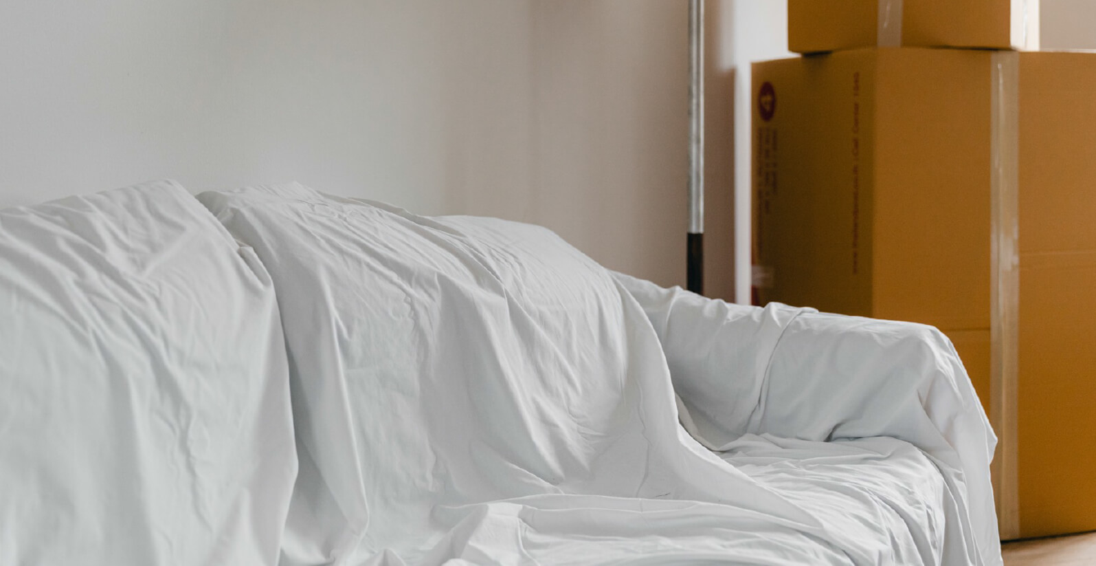Couch covered with sheet with moving boxes